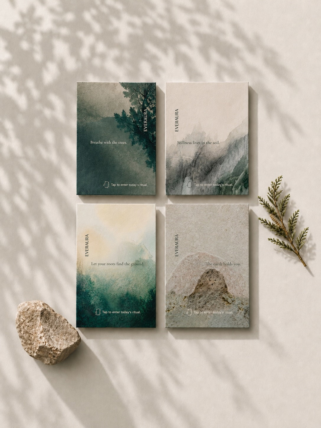 The four EverAura Grounding ritual card designs laid together with stone and cedar. Breathe with the trees, Stillness lives in the soil, Let your roots find the ground, and The earth holds you.