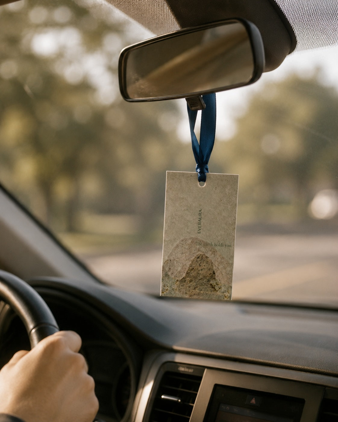 EverAura Grounding ritual card hanging from a car rearview mirror — a portable grounding nature meditation and calming scent for the daily drive.