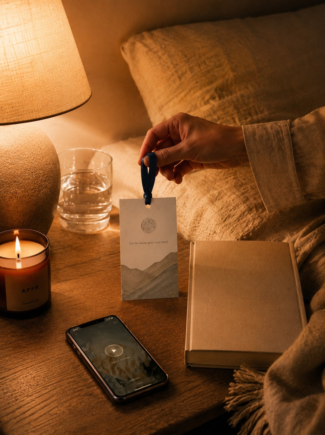 EverAura Moon Water ritual card on a candlelit nightstand at night with a glass of water and the meditation app. Let the moon quiet your mind, an evening one minute nature meditation and scent card.