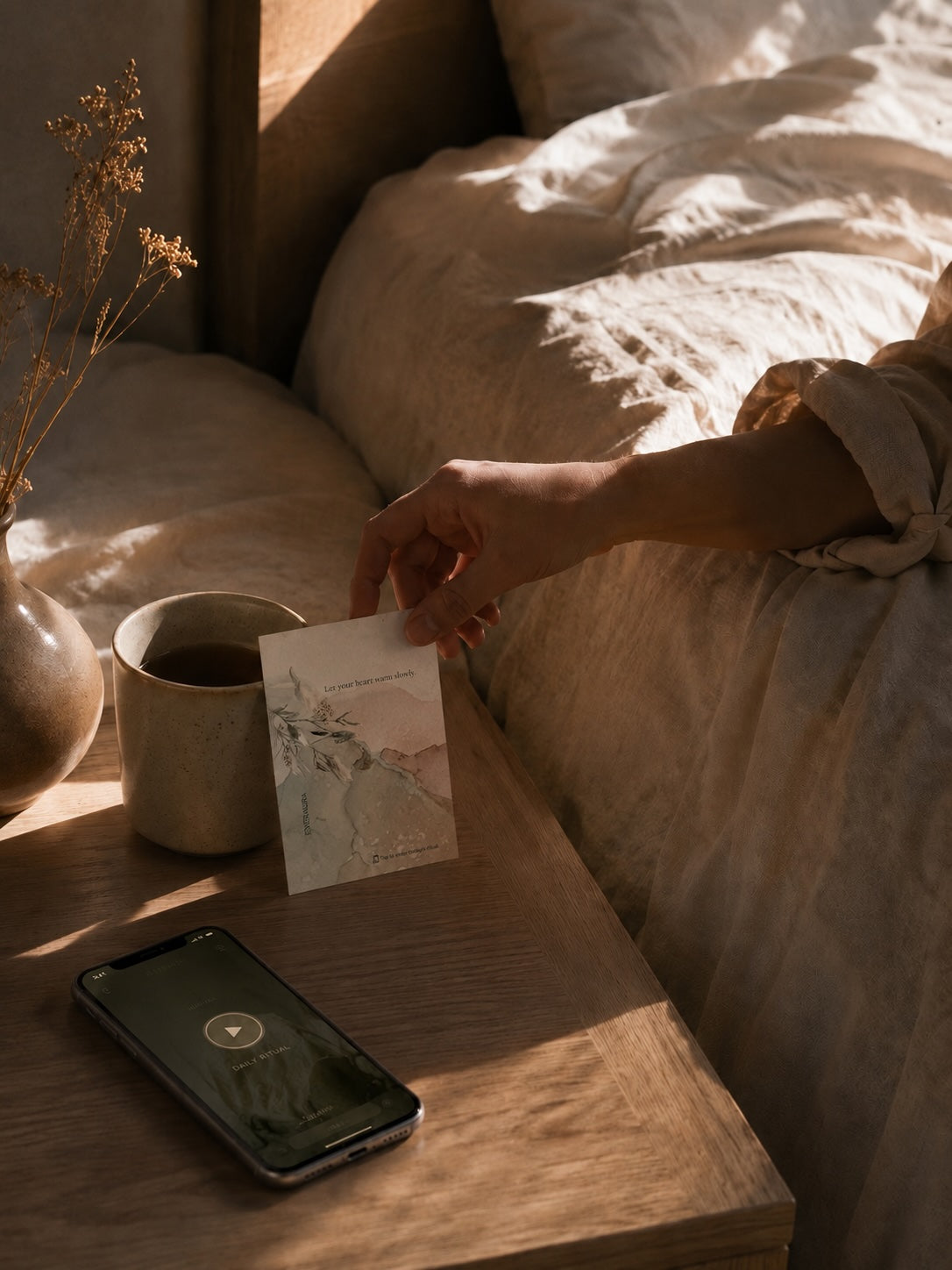 EverAura Radiant Heart ritual card on a sunlit nightstand with coffee and the meditation app. Let your heart warm slowly, a one minute nature meditation and scent card.